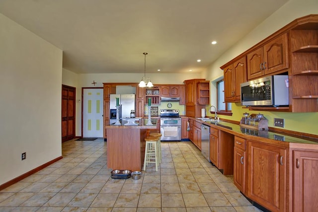 kitchen with sink, pendant lighting, a breakfast bar, a kitchen island, and appliances with stainless steel finishes