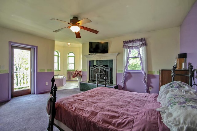 carpeted bedroom featuring ceiling fan and a fireplace