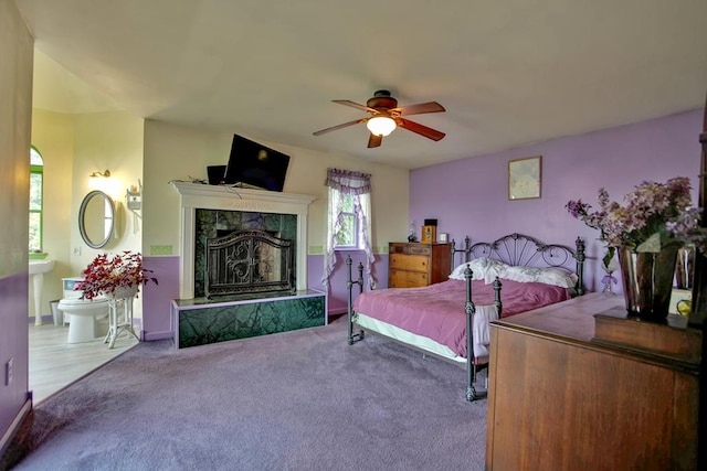 carpeted bedroom featuring ceiling fan and a tiled fireplace