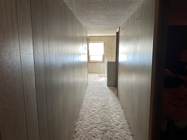 corridor featuring wooden walls and light colored carpet