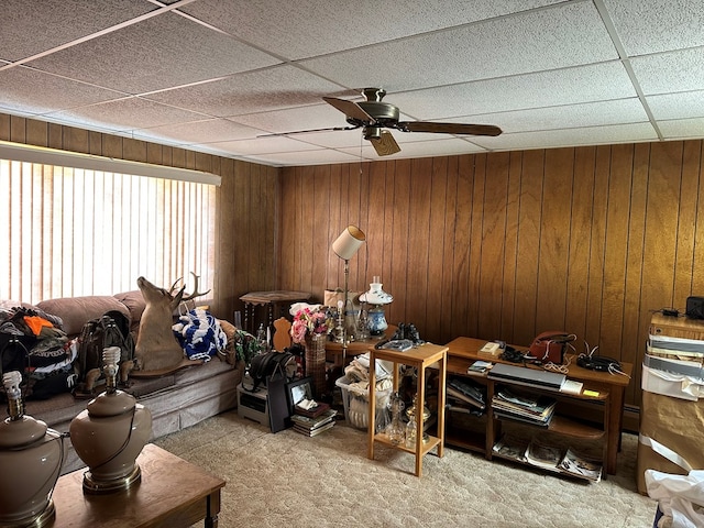 carpeted living room with ceiling fan and wooden walls