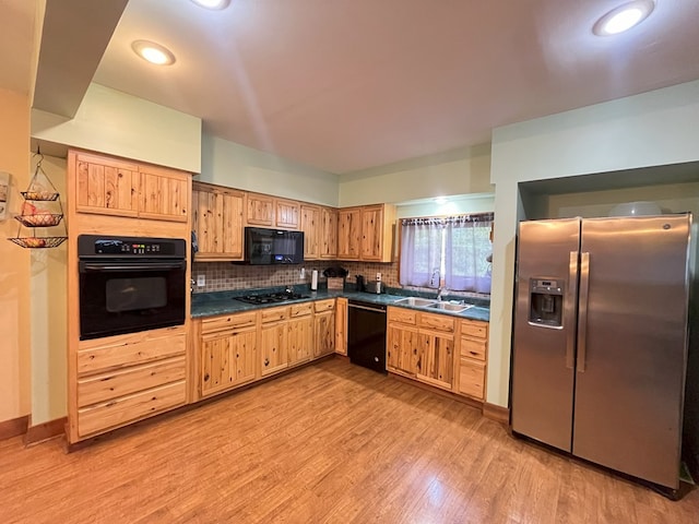 kitchen featuring backsplash, sink, black appliances, and light hardwood / wood-style floors