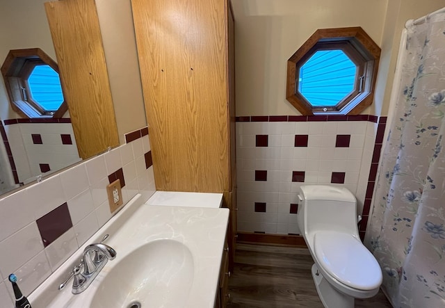 bathroom with sink, a shower with shower curtain, toilet, tile walls, and hardwood / wood-style flooring