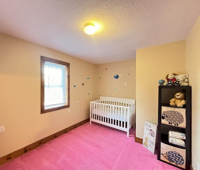 bedroom with a textured ceiling, carpet floors, and a crib