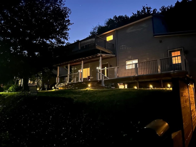 back house at dusk with a yard and a balcony