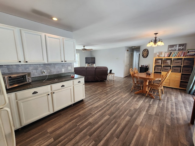 kitchen with white cabinets, dark countertops, open floor plan, dark wood-style flooring, and pendant lighting