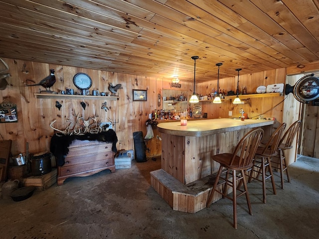 bar featuring wooden ceiling, hanging light fixtures, wooden walls, and a dry bar