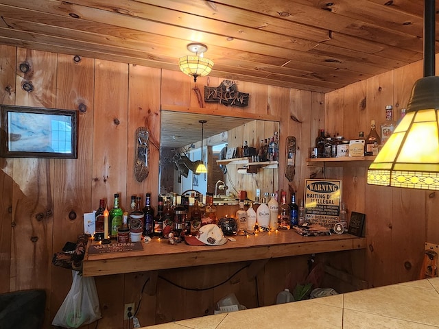 bar featuring hanging light fixtures, a bar, wooden ceiling, and wooden walls