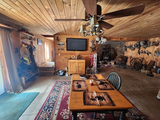 dining space with wood walls, wooden ceiling, a wood stove, and a ceiling fan