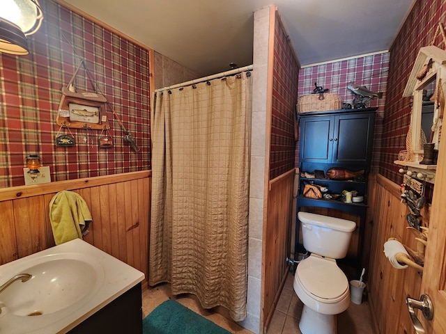 bathroom with a wainscoted wall, a shower with shower curtain, toilet, vanity, and tile patterned flooring