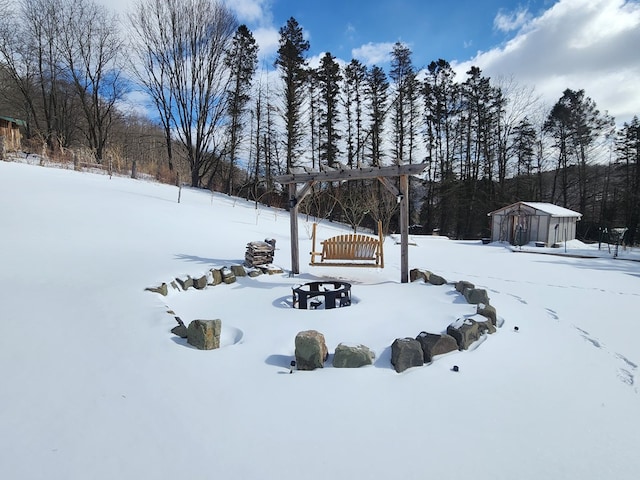 yard layered in snow with a garage, a shed, and an outdoor structure