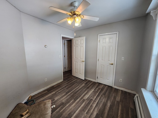 unfurnished bedroom featuring a baseboard radiator, dark wood finished floors, a ceiling fan, and baseboards