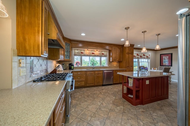 kitchen with sink, ornamental molding, a center island, light stone counters, and stainless steel appliances