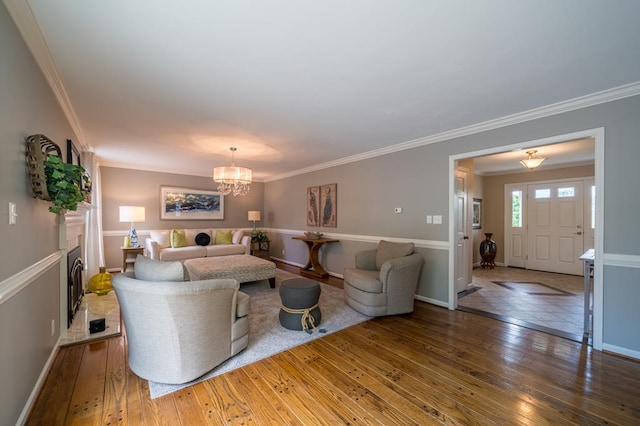 living room with hardwood / wood-style flooring, ornamental molding, and a notable chandelier