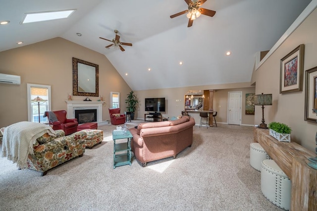 carpeted living room with a wall mounted air conditioner, a skylight, high vaulted ceiling, and ceiling fan