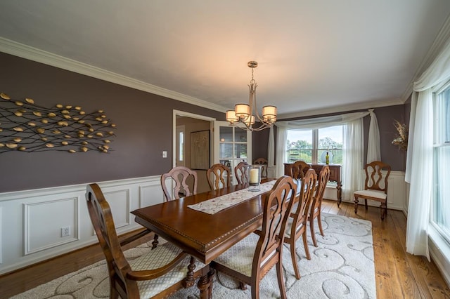 dining area with crown molding, light hardwood / wood-style floors, and an inviting chandelier