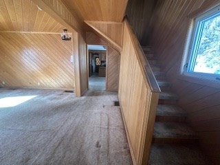 staircase featuring carpet floors, wooden walls, and wooden ceiling