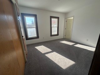 unfurnished room featuring dark colored carpet