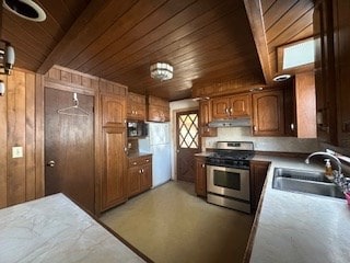 kitchen with gas stove, sink, wooden walls, and wood ceiling