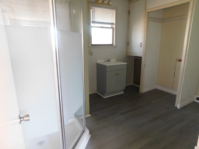 bathroom featuring a stall shower, vanity, baseboards, and wood finished floors