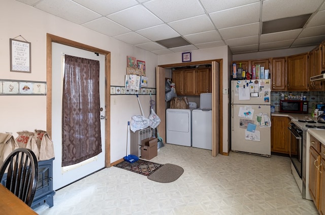 kitchen with a paneled ceiling, white refrigerator, stove, and washing machine and clothes dryer