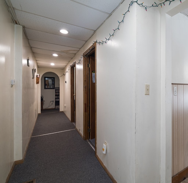 corridor featuring a paneled ceiling and carpet floors