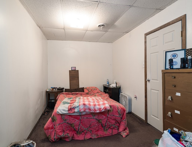 bedroom with a drop ceiling and dark colored carpet