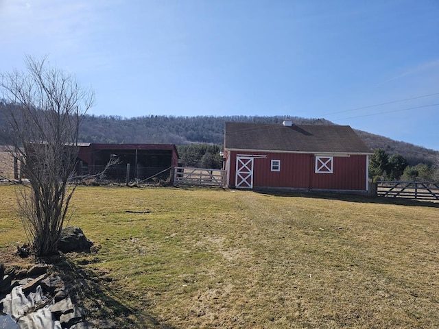 view of barn featuring a lawn and fence