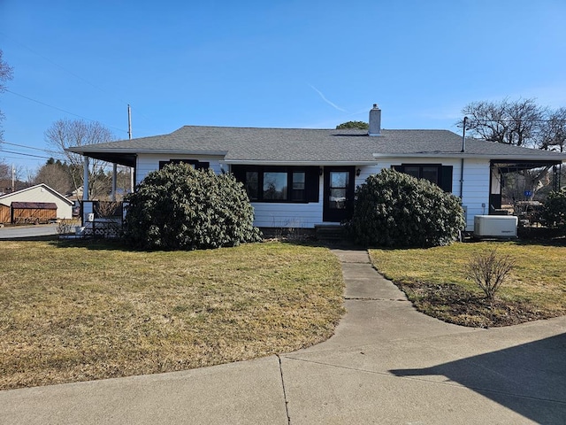 view of front of home with a chimney, a front yard, and a shingled roof