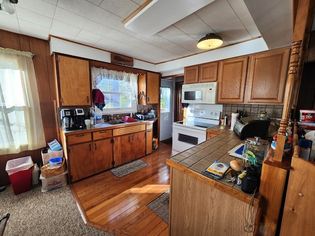 kitchen featuring tile countertops, hardwood / wood-style floors, white appliances, and sink