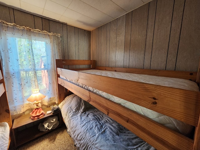 unfurnished bedroom with carpet and wood walls