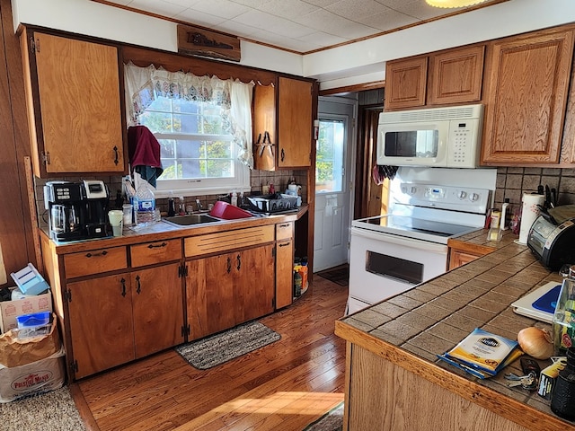 kitchen with sink, dark hardwood / wood-style flooring, backsplash, crown molding, and white appliances