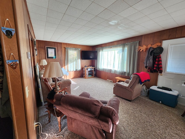 carpeted living room featuring wooden walls