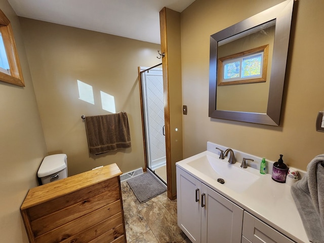 bathroom with vanity, a shower with shower door, and toilet