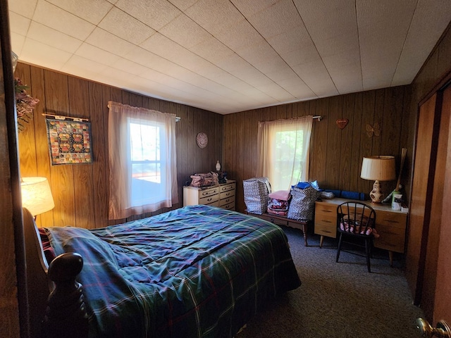 bedroom featuring dark carpet and wood walls