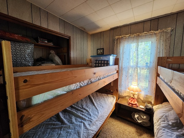 bedroom with light carpet and wooden walls