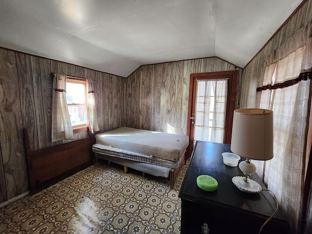 bedroom with vaulted ceiling and wood walls