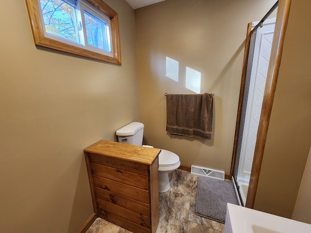 bathroom with a shower with door and toilet