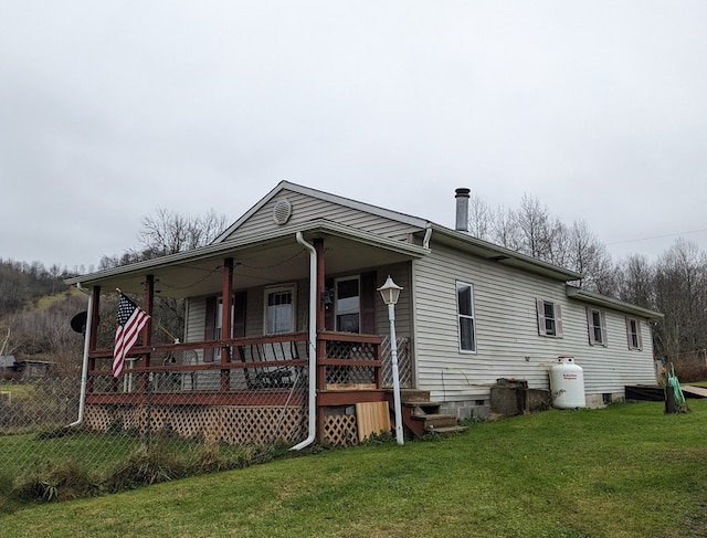 rear view of house featuring covered porch and a lawn