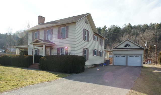 colonial home featuring a front yard, an outdoor structure, and a garage