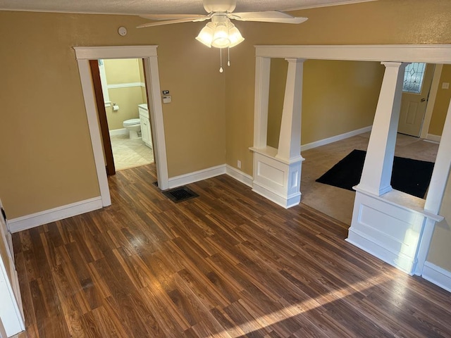 unfurnished living room with dark wood-style flooring, ornate columns, a ceiling fan, and visible vents