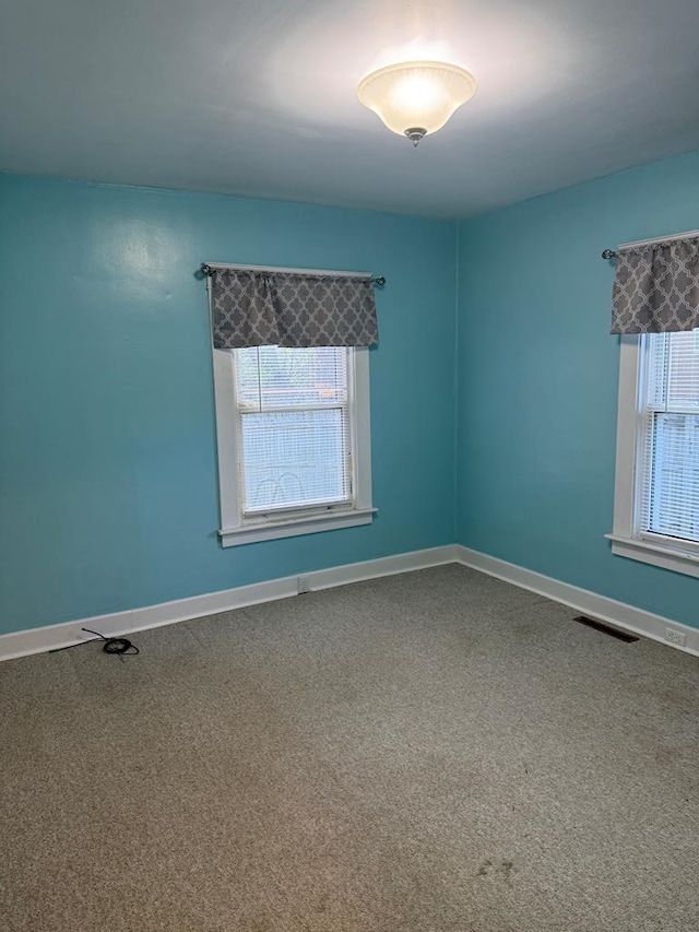 spare room with carpet floors, baseboards, and visible vents