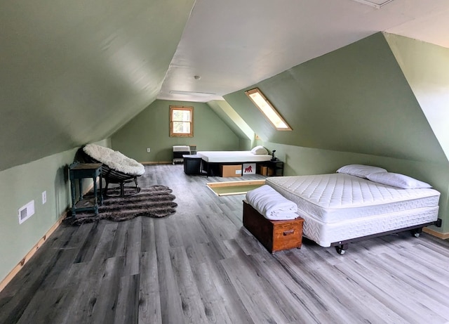 bedroom with lofted ceiling, visible vents, baseboards, and wood finished floors