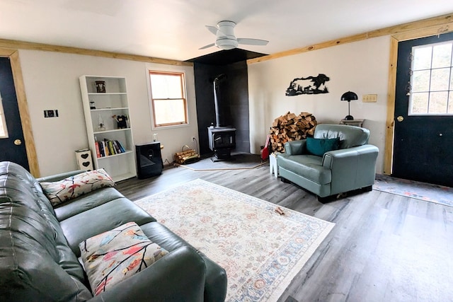 living area featuring a wood stove, a ceiling fan, and wood finished floors