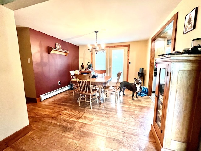 dining space with hardwood / wood-style floors, a notable chandelier, and a baseboard radiator