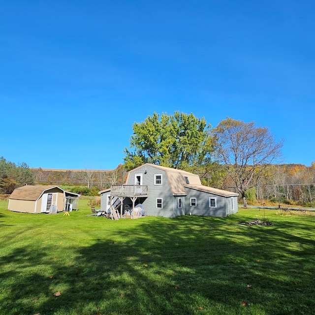 rear view of house featuring a yard, a deck, and a storage shed