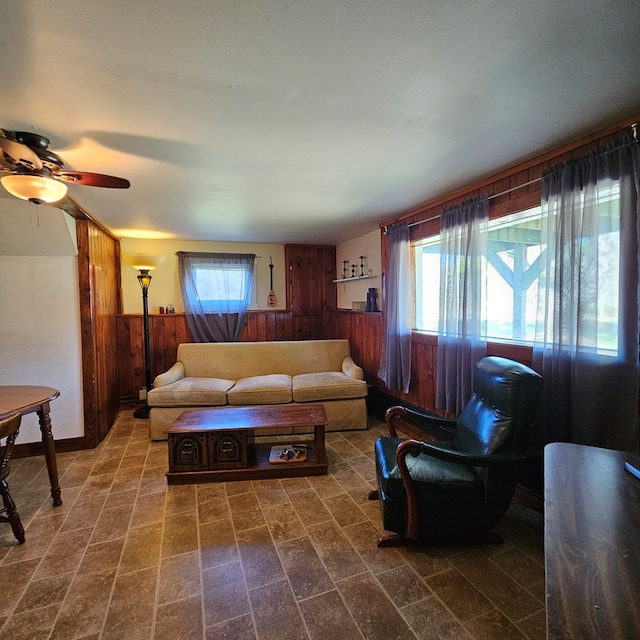 living room with ceiling fan and wooden walls