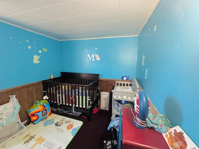 bedroom with a crib and wood walls