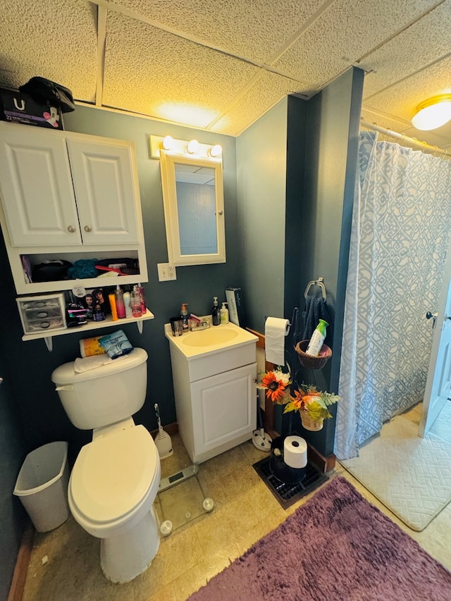 bathroom with a drop ceiling, vanity, and toilet