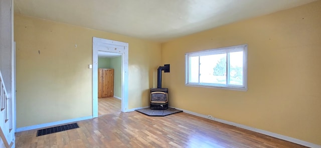 unfurnished living room with light wood-type flooring and a wood stove